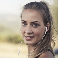 Junge sportliche Frau mit Kopfhörern schaut in die Kamera